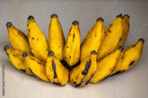 A bunch of ripe yellow bananas on a wooden background. Bananas are rich in potassium and other important minerals and vitamins that help your body perform critical functions. 