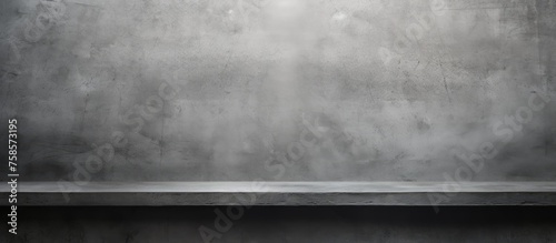 A wooden rectangular table is placed in front of a grey concrete wall, under a cloudy sky. The landscape includes asphalt ground and various tints and shades photo