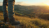 Legs of a traveler in hiking boots standing in the mountains with the beautiful view of the green hills