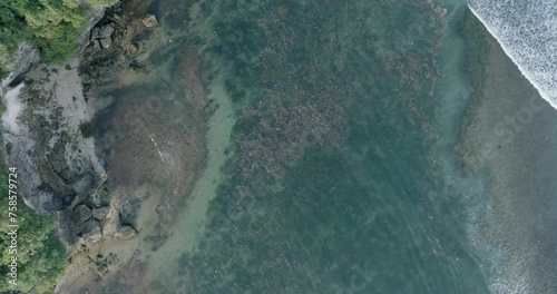 Top down quickly descending drone shot of polluted water filled with trash floating over dead coral reef in the turqouise tropical water of  Bali Indonesia photo