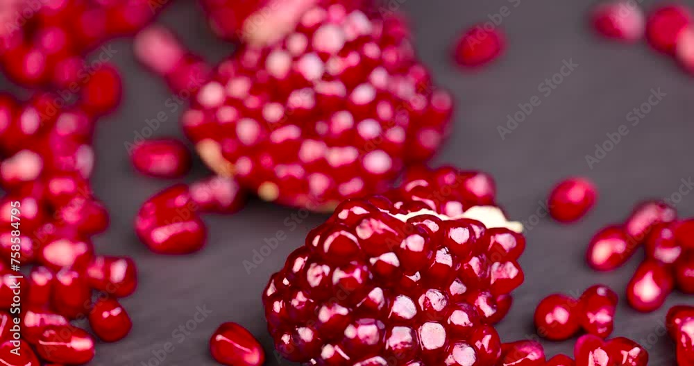 red grains of peeled pomegranate fruit, large sweet and juicy pomegranate seeds on a table made of black slate
