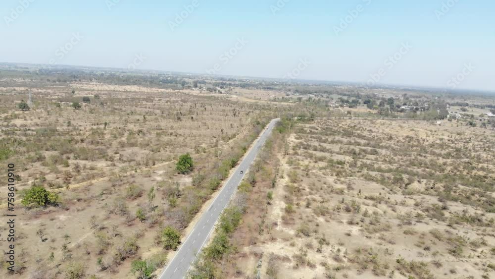 Aerial shot of beautiful vast barren land near Charu village in Chatra, Jharkhand, India with a road passing in the middle and a bike travelling. Jharkhand tourism. Aerial shot of beautiful vast barren land near Charu village in Chatra, Jharkhand, India with a road passing in the middle and a bike travelling. Jharkhand tourism.