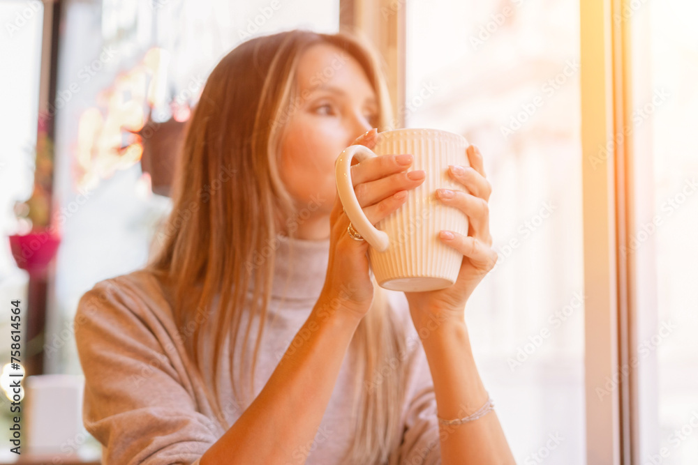 Woman with blonde hair sips cappuccino in a cafe. She is holding the glass up to her face, taking a sip of the drink. Woman with blonde hair sips cappuccino in a cafe. She is holding the glass up to her face, taking a sip of the drink.