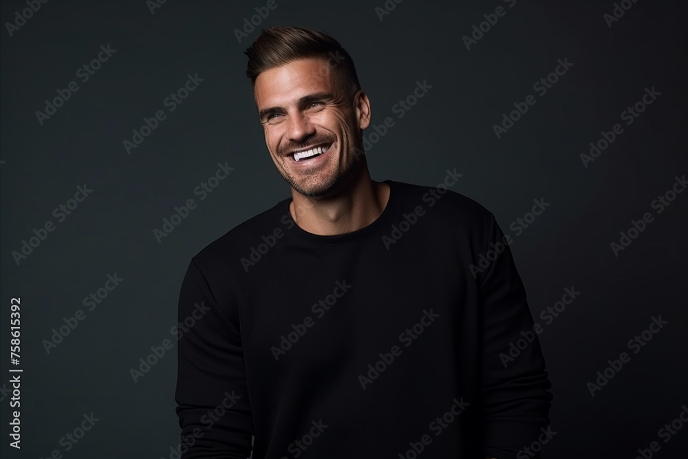 Portrait of a happy young man in black sweater over dark background.
