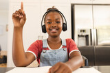 A young African American girl raises her hand during a lesson on a video call online school lesson
