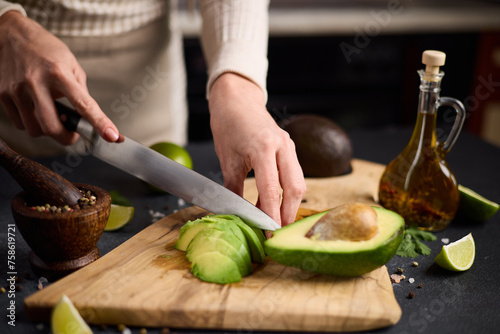 Salsa recipe - Woman Cutting slicing fresh green avocado fruit with knife on a wooden board at domestic kitchen