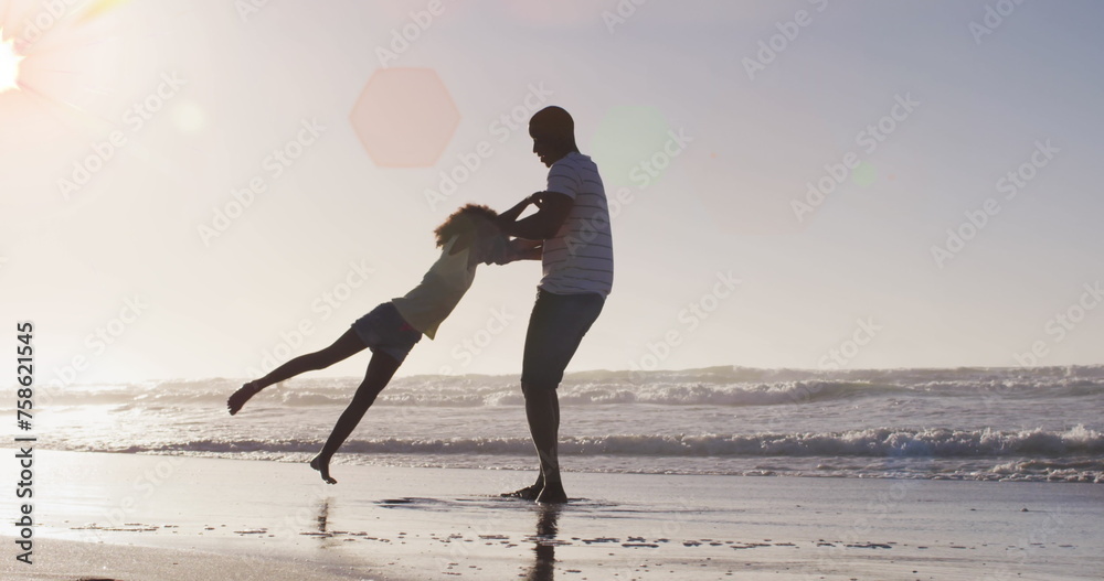 Fototapeta premium Image of spots over happy african american father with daughter on sunny beach
