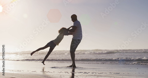 Image of spots over happy african american father with daughter on sunny beach
