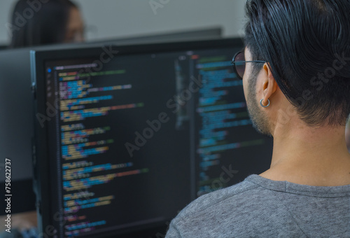 Asian prompt engineer developer coding app with software data sitting in front of computer monitor at office