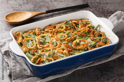 Obraz na płótnie Green bean casserole with cheesy mushroom sauce and topped with crispy onions close-up in a baking dish on the table. horizontal w salonie