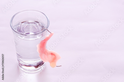 Close up acrylic dentures immersed in a glass of water photo