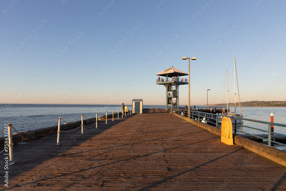 Naklejka premium Tourists enjoying the evening views of the Pacific Ocean and the city of Port Angeles from the famous observation tower on the pier