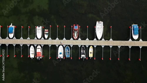 small harbor with many small boats, man walks slowly across the jetty, ocean, visby, sweden, drone photo