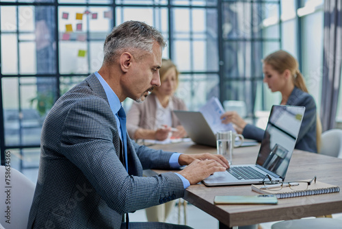 Confident businessman sitting at conference table in modern office