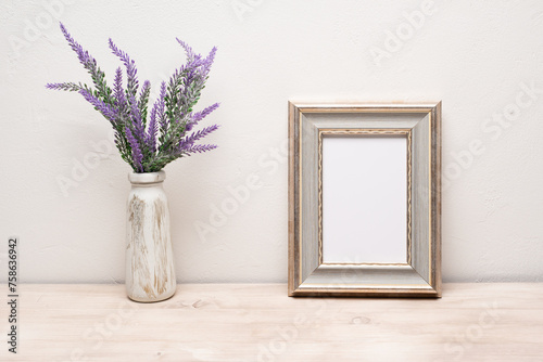 The layout of the frame with a purple bouquet of flowers. A mock-up of an old white portrait frame. Layout of an empty white frame for the design.