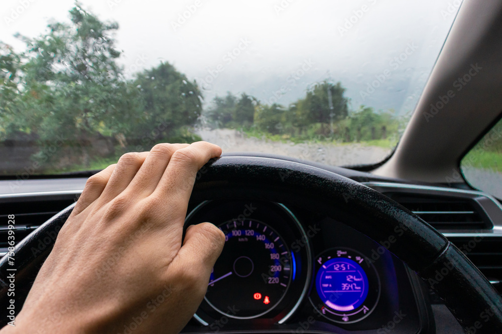 Travel concept. Man's hand inside a car on a rainy day with nature background. After some edits.