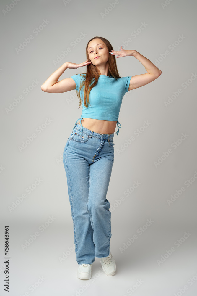 Young woman in blue T-shirt posing to camera on gray background Young woman in blue T-shirt posing to camera on gray background
