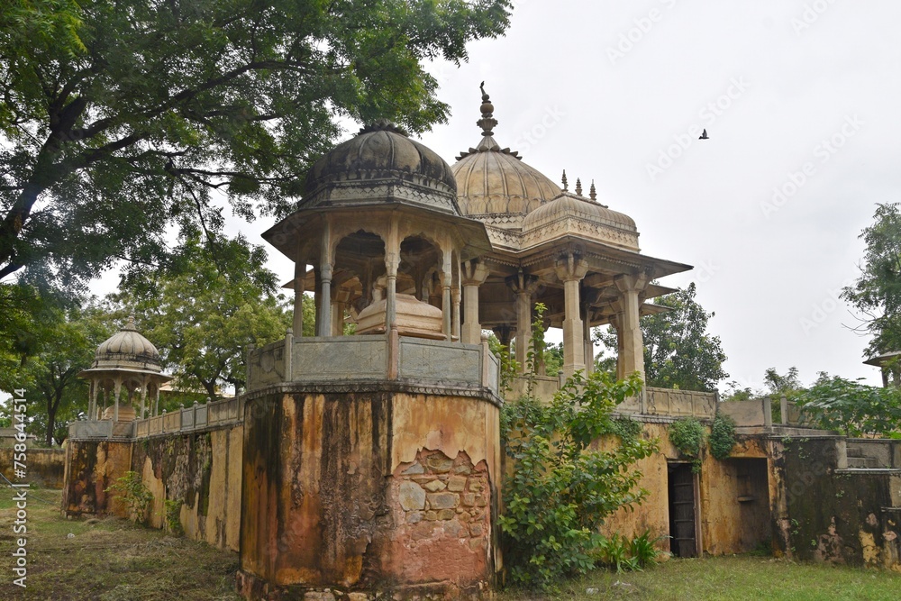 Obraz premium Majestic Royal Cenotaphs Amidst Verdant Greenery Under Cloudy Skies at Maharani Ki Chhatri ,Jaipur, Rajasthan, India