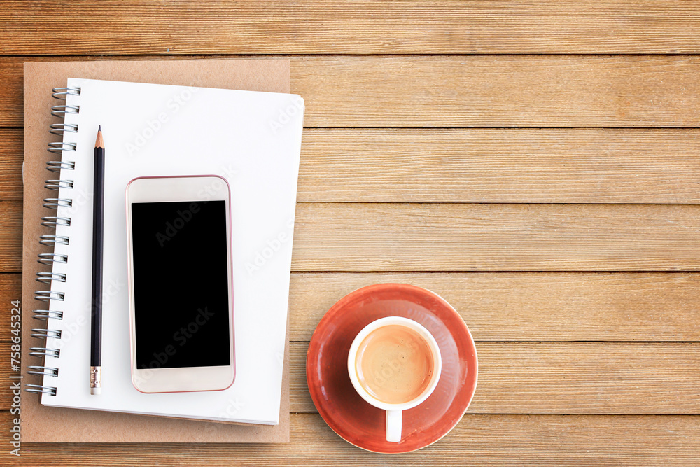 Empty blank paper notebook and smart phone on brown wooden table Empty blank paper notebook and smart phone on brown wooden table