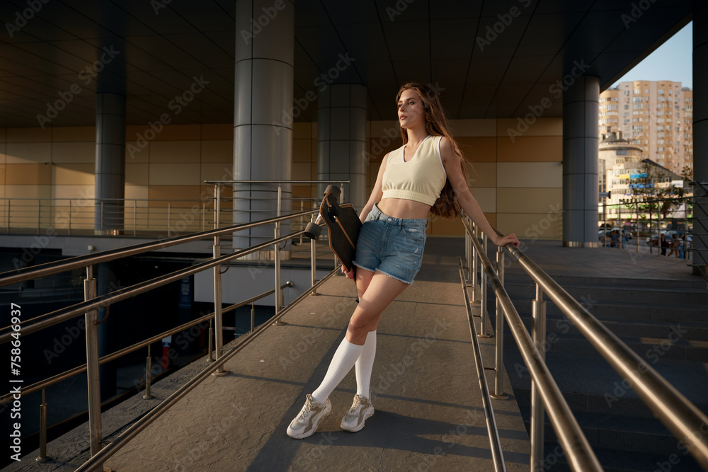 Obraz premium Young female with skateboard, active summer vacation concept