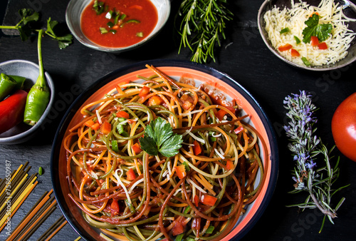 bunte spaghetti auf bunten Teller mit rosmarin, tomaten, paprika und sauce