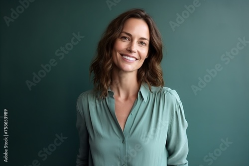 Portrait of a smiling business woman standing against a green background. © Igor