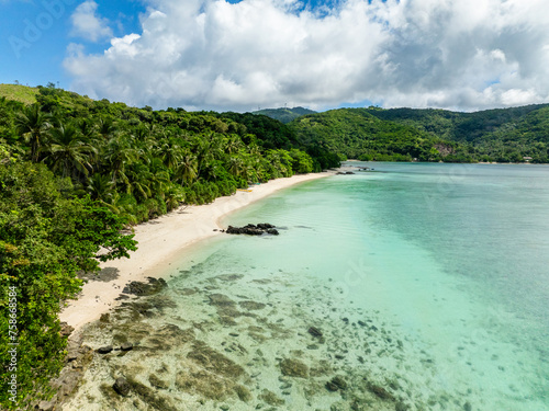 Coastline with coconut trees and white sandy beach. Turquoise sea water in Romblon Island. Romblon, Philippines.