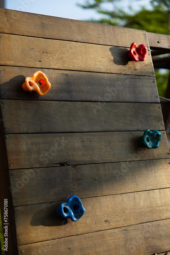 Climbing wall of wooden planks with colored grips, Rock Climbing in Playground for child. evening light.