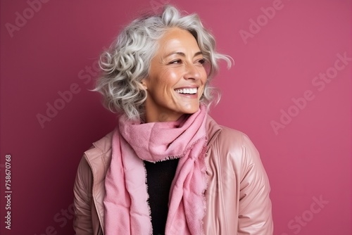 Portrait of a happy senior woman laughing and looking up over pink background