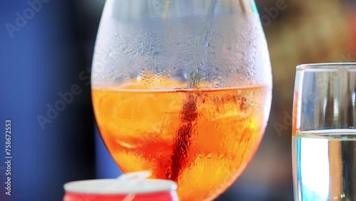 Orange orange cocktail with alcohol and ice in a transparent glass glass. A cocktail based on the famous orange vermouth with a bittersweet taste. Slow motion photo