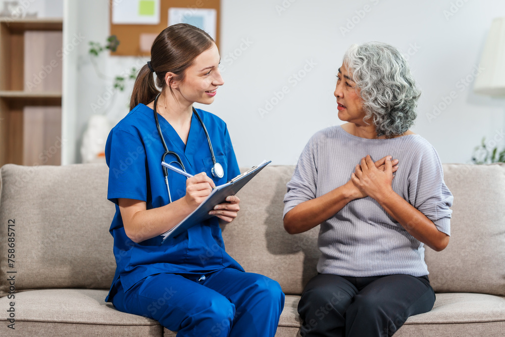 Fototapeta premium Caucasian teenager female doctor consults with and Asian elderly patient on medical history, discussing headaches, chest pain, coughing, sneezing, stomach pain, and neck pain while seated on a sofa.