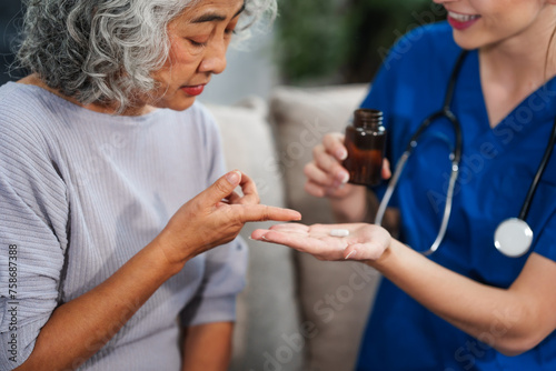 Caucasian female doctor introduces medicine to an elderly Asian patient while seated on a sofa  providing guidance and information about the prescribed medication.