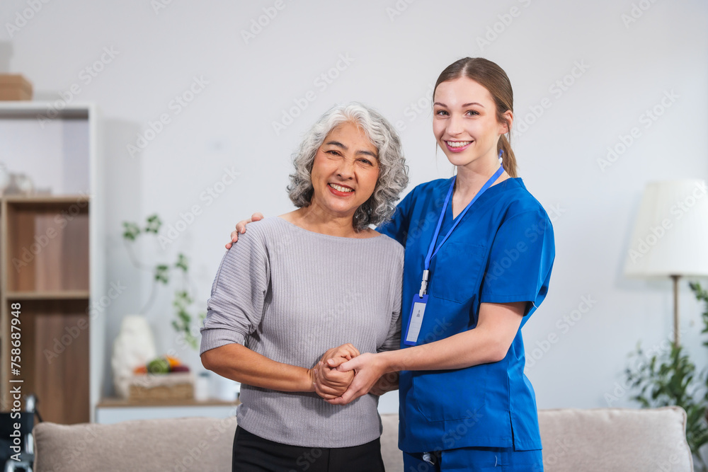 Caucasian female doctor assists in supporting an elderly Asian patient while they both sit on the sofa, ensuring comfort and stability during the interaction. Caucasian female doctor assists in supporting an elderly Asian patient while they both sit on the sofa, ensuring comfort and stability during the interaction.