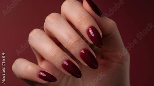 A woman s hand with a beautiful burgundy manicure.