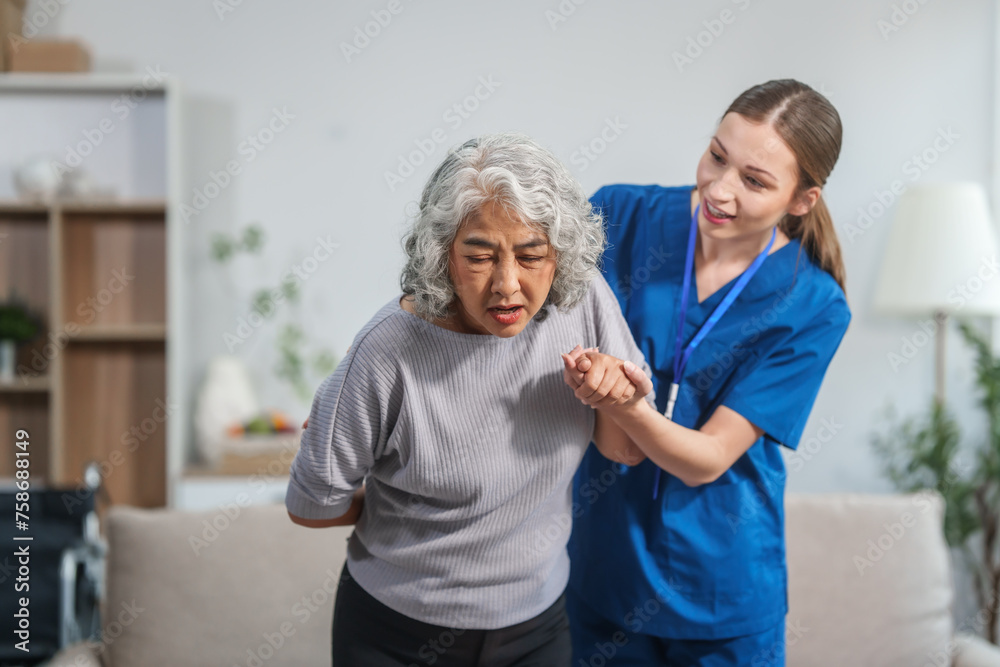 Caucasian female doctor assists in supporting an elderly Asian patient while they both sit on the sofa, ensuring comfort and stability during the interaction. Caucasian female doctor assists in supporting an elderly Asian patient while they both sit on the sofa, ensuring comfort and stability during the interaction.