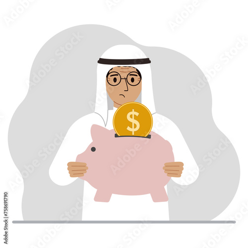 Sad muslim man holds a piggy bank, a coin falls into the piggy bank. The concept of saving finance, savings, investing finances.