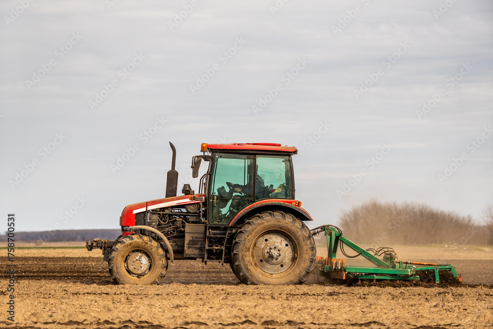 A modern tractor tilling farmland, preparing the soil for planting crops A modern tractor tilling farmland, preparing the soil for planting crops