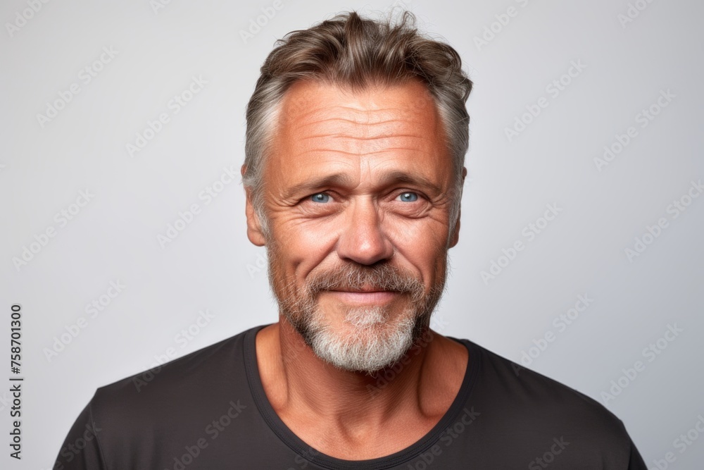 Handsome middle aged man with grey beard and mustache looking at camera on grey background