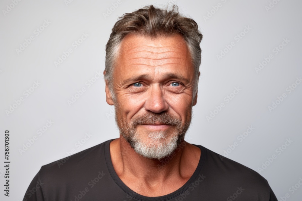 Handsome middle aged man with grey beard and mustache looking at camera on grey background Handsome middle aged man with grey beard and mustache looking at camera on grey background