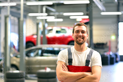 portrait of a smiling car mechanic in car workshop in woking clothes - occupation workmen