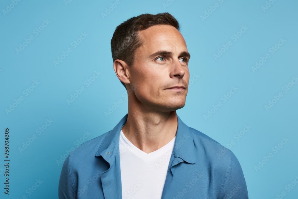 Portrait of handsome caucasian man in blue shirt looking away over blue background Portrait of handsome caucasian man in blue shirt looking away over blue background