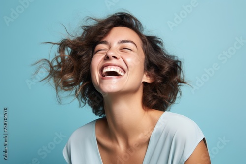 Portrait of a happy young woman with flying hair over blue background photo