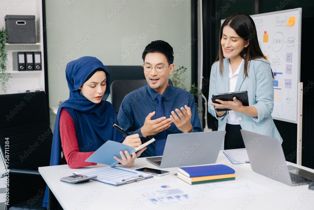 Happy businesspeople while collaborating on a new project in an office. Group of diverse businesspeople using a laptop and tablet .. Happy businesspeople while collaborating on a new project in an office. Group of diverse businesspeople using a laptop and tablet ..