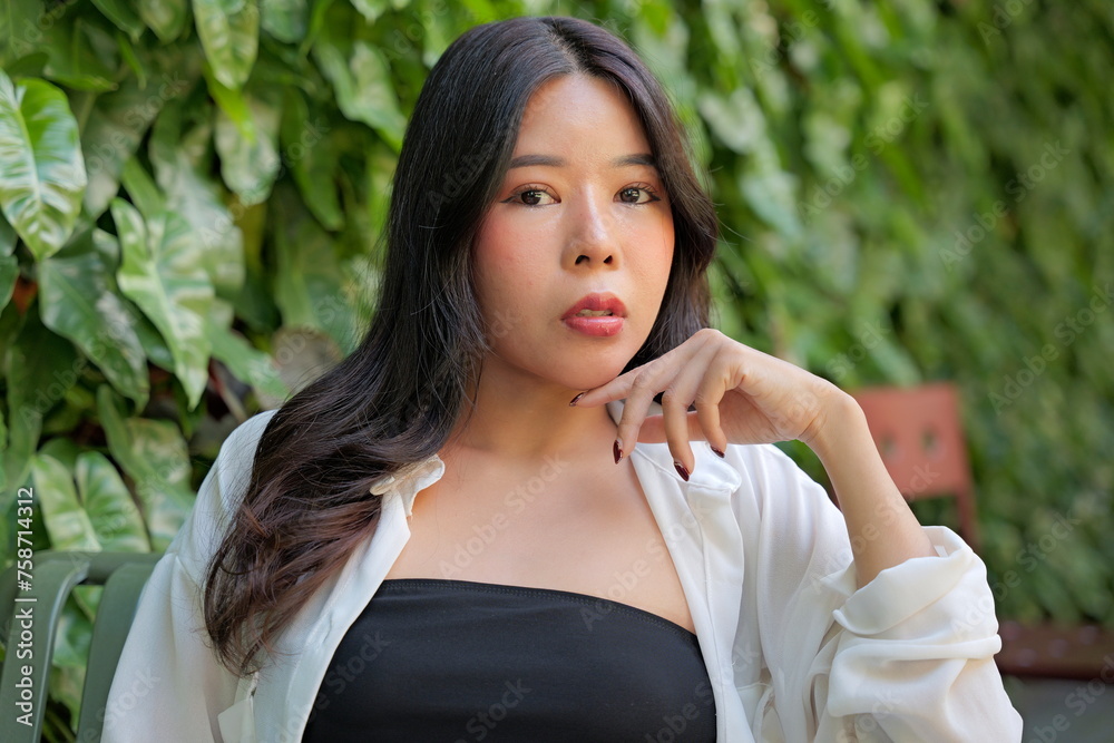 Portrait of beautiful young Asian woman posing in front of green hedge Portrait of beautiful young Asian woman posing in front of green hedge