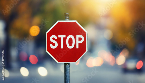 Stop road sign. Red octagon with white lettering. Blurred bokeh on background.