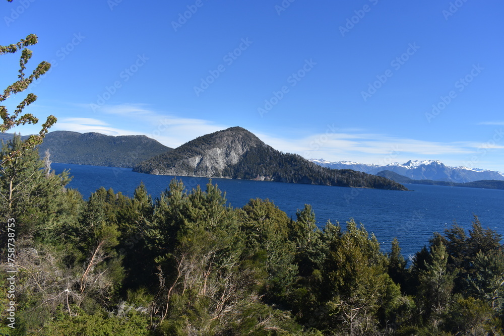 montaña con el lago a su alrededor visto desde otra isla con arboles y cielo despejado