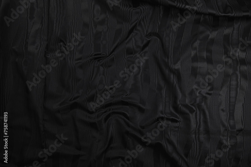 Texture of black taffeta (silk) fabric with black stripes pattern, top view. Background, texture of draped dressy fabric with shining black stripes pattern. photo