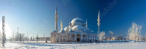A mosque in a winter landscape, its domes and minarets covered in snow, against the clear blue sky of a cold day