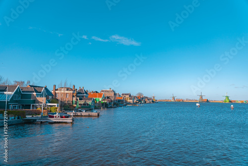 Beautiful Dutch scenery panorama of Zaanse Schans village in Netherlands in spring time. Ancient windmills at the water's edge in the background with the blue sky in sunny weather