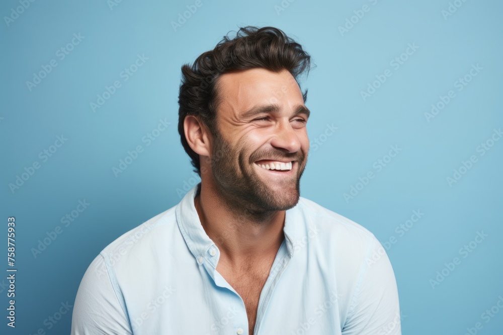Portrait of happy man laughing and looking at camera over blue background Portrait of happy man laughing and looking at camera over blue background